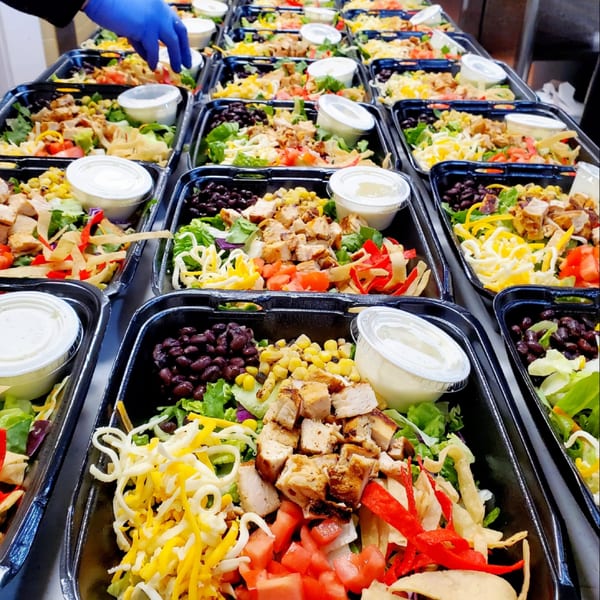 Rows of Maria Rita's Tex-Mex chicken salads with black beans, corn, cheese, and dressing.