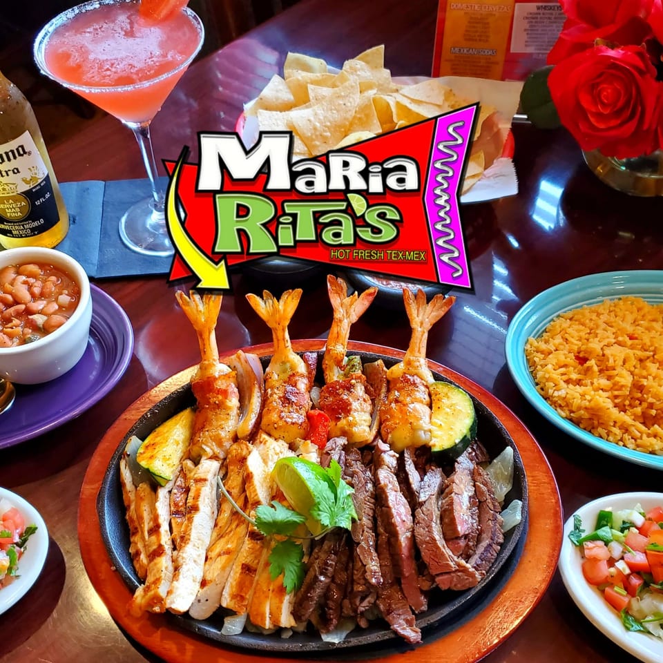 Sizzling fajitas with shrimp, chicken, and steak, alongside rice, beans, chips, and a margarita.
