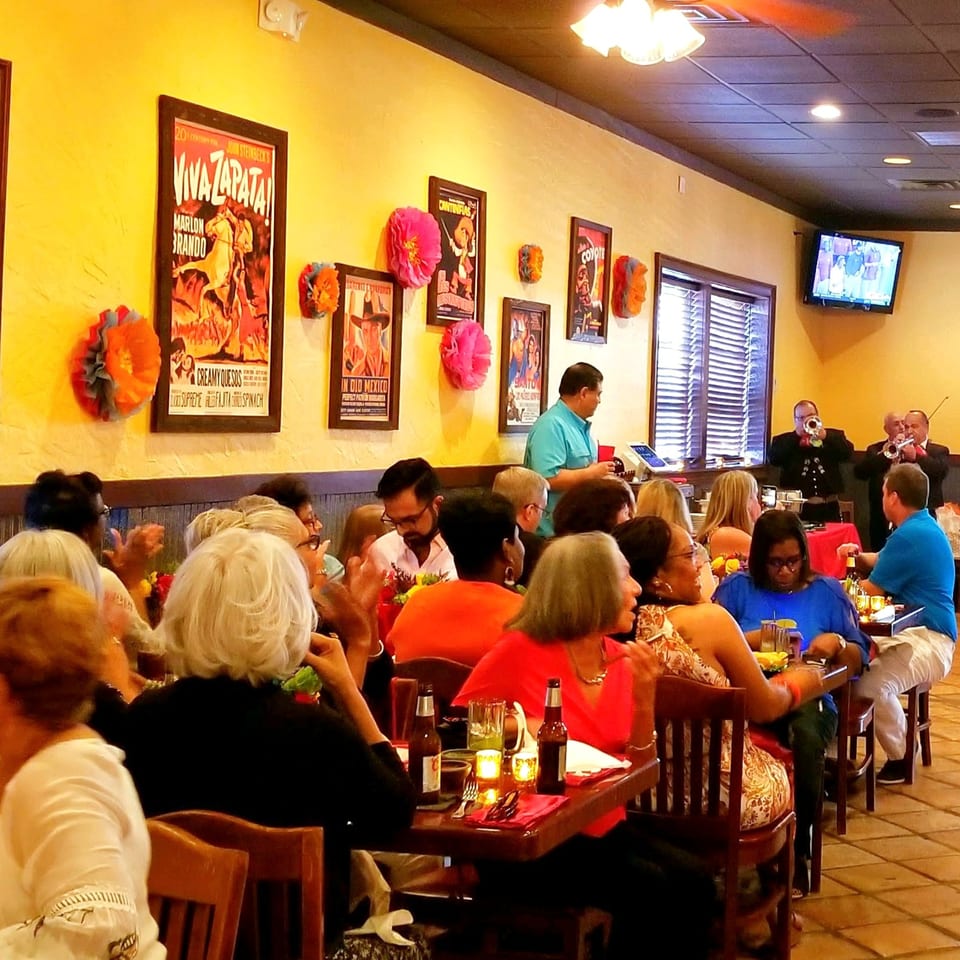 Diners enjoy live mariachi music in a vibrant Maria Rita's Tex-Mex restaurant with movie posters.