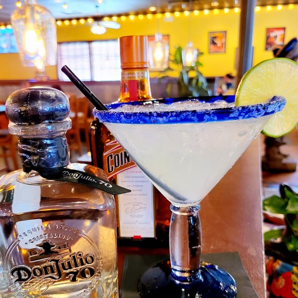 Maria Rita's Tex-Mex margarita with a lime slice, Don Julio 70, and Cointreau bottles.
