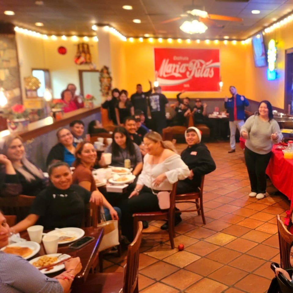 Diners enjoying a lively meal at Maria Rita's Tex-Mex restaurant, with a large branded sign visible.